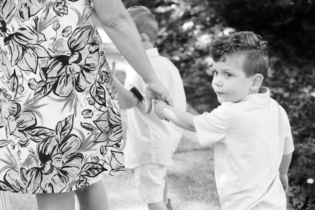 boy walking holding hands with mom and looking back