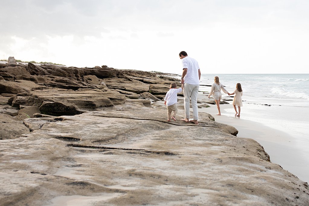 family walking along the rocks by the ocean at their sweet family beach session