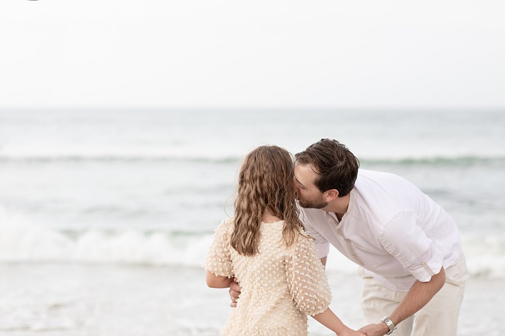 dad whispering in daughters ear at the beach