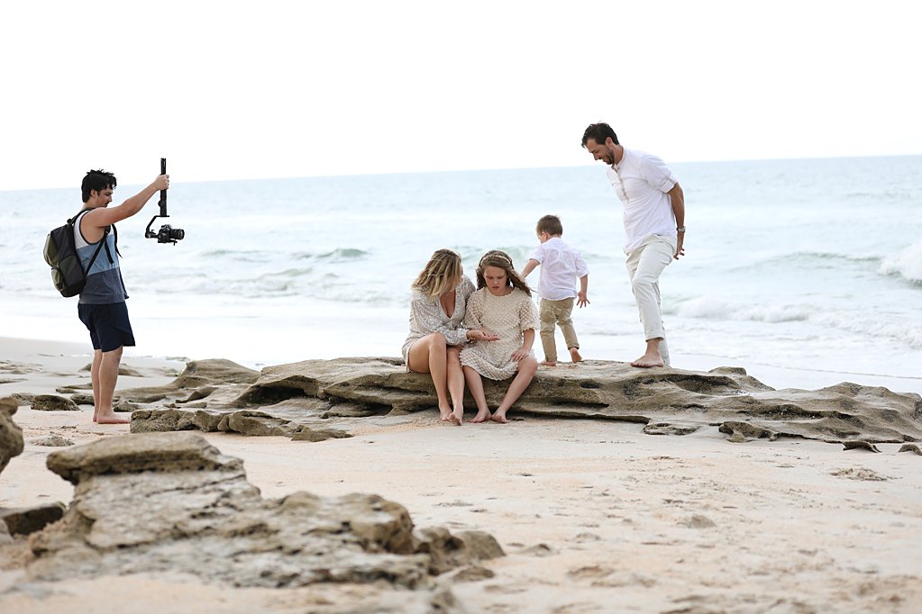 behind the scenes a videographer filming a family on rocks