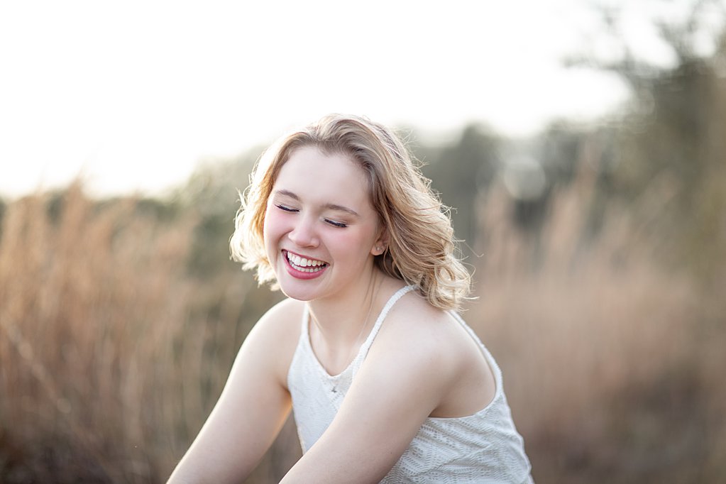girl laughing in field at senior session