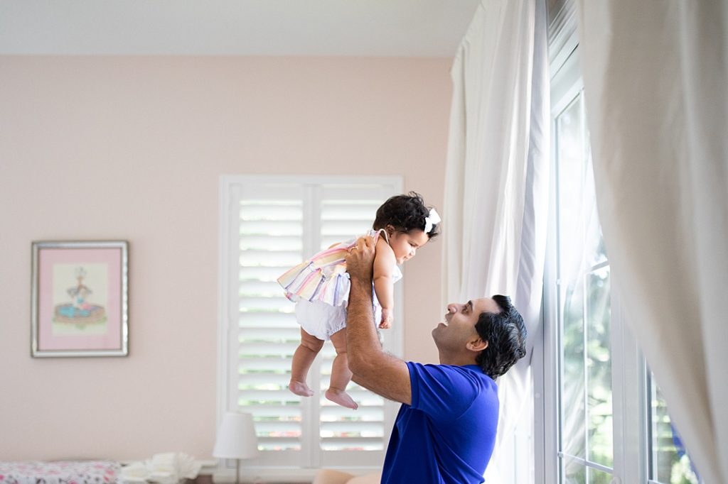 dad lifts baby girl while smiling