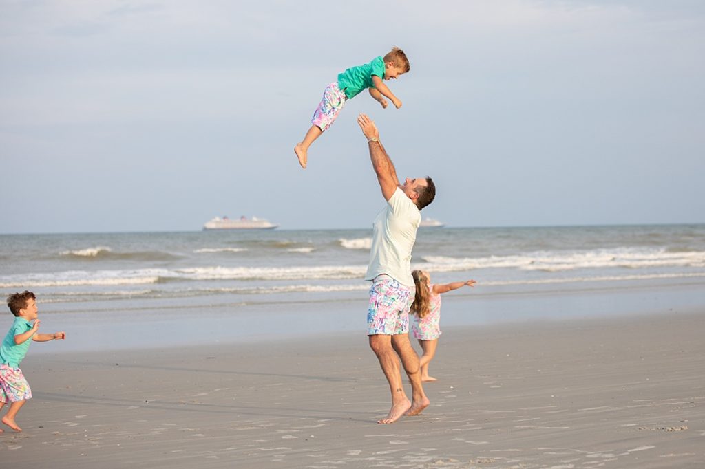 dad tossing son into air at beach