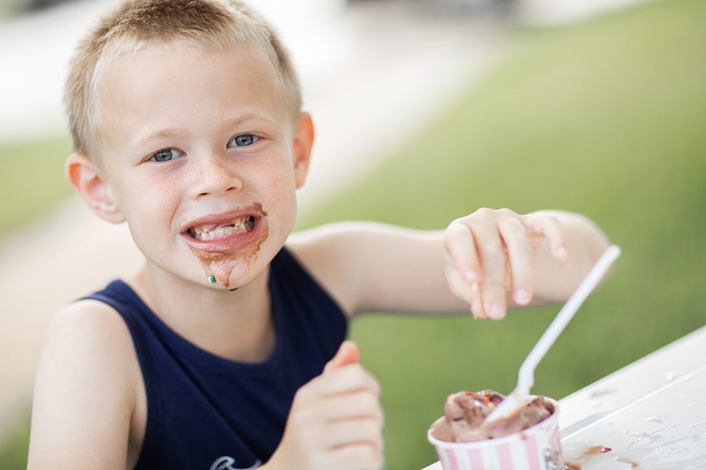 boy showing his toothless smile while eating ice cream