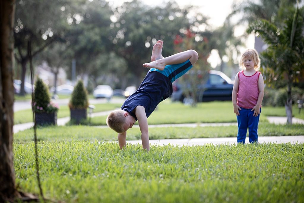 brother doing cartwheel while sister watches